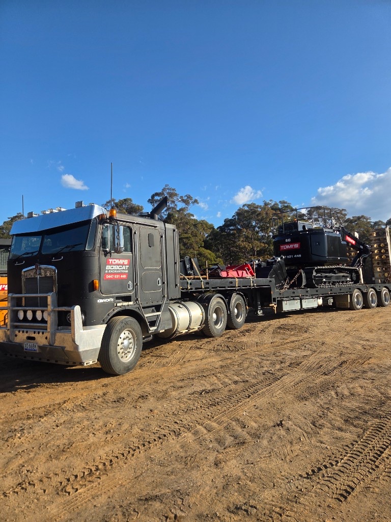 Kenworth truck transporting a Tomi's excavator
